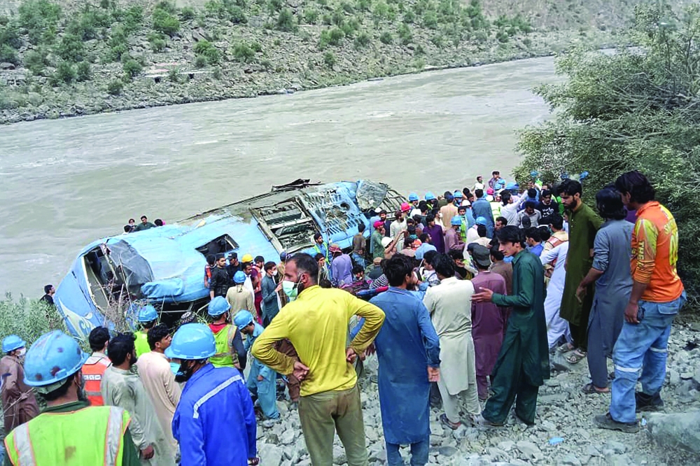 Rescue workers and onlookers gather around a wreck after a bus plunged into a ravine following a bomb explosion, in Kohistan district of Khyber-Paktunkhwa province, on Wednesday. - AFP
