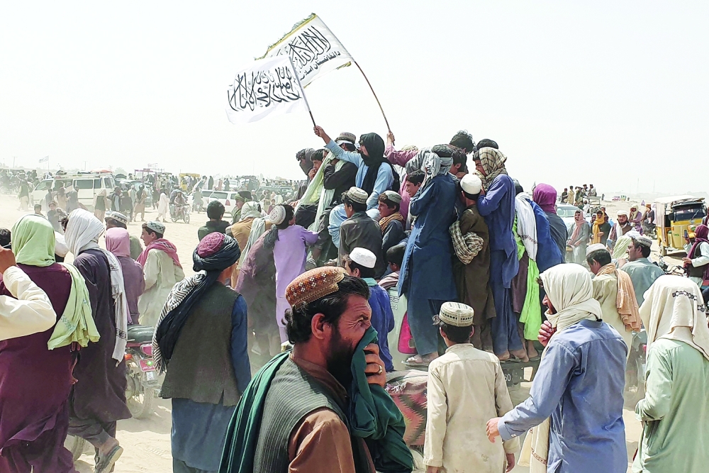 People wave Taliban flags as they drive through the Pakistani border town of Chaman on Wednesday. - AFP 