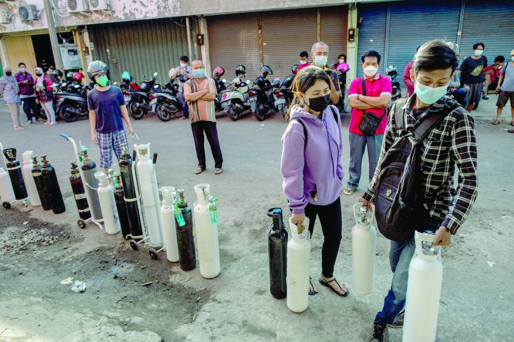 Residents queue up to get oxygen tanks refilled at a refilling station in Surabaya on Thursday. -- AFP
