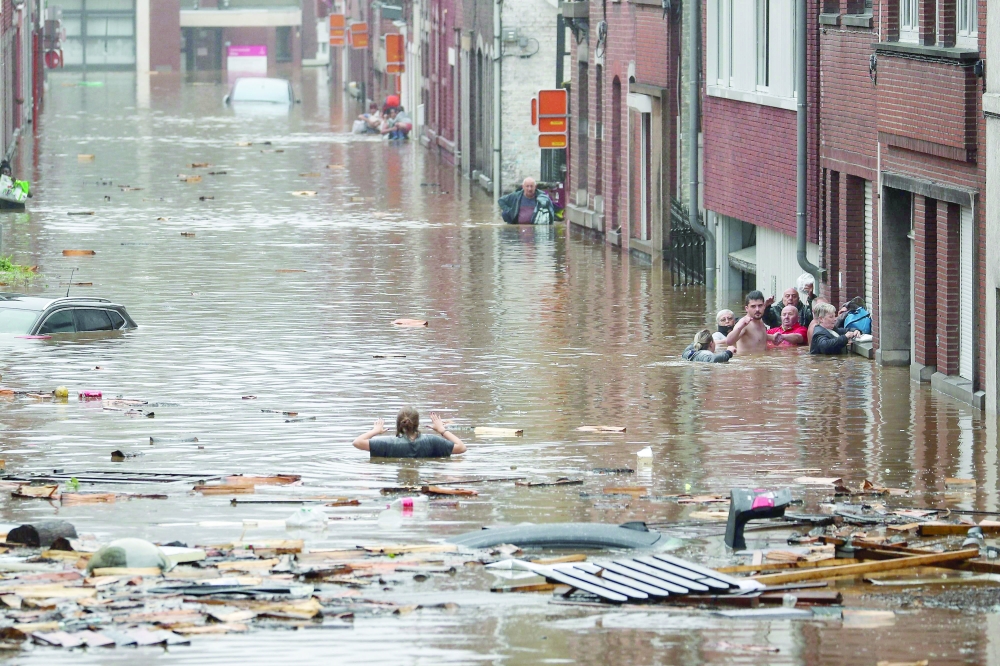 A woman is trying to move in a flooded street following heavy rains in Liege, Belgium on Thursday. -- AFP
