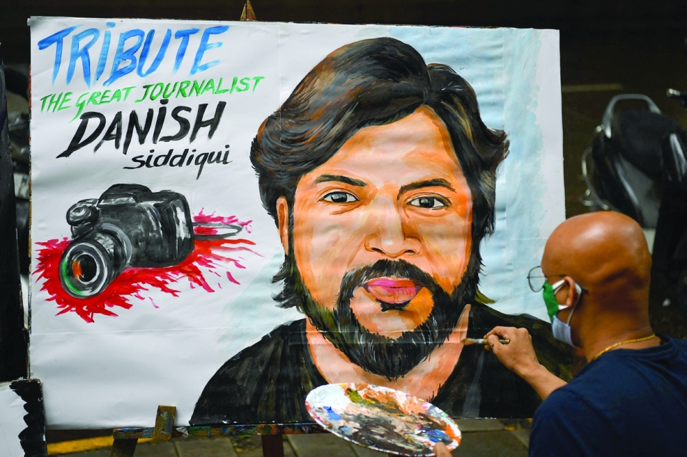 An art teacher gives finishing touches to a painting of Reuters journalist Danish Siddiqui as a tribute outside an art school in Mumbai. - AFP