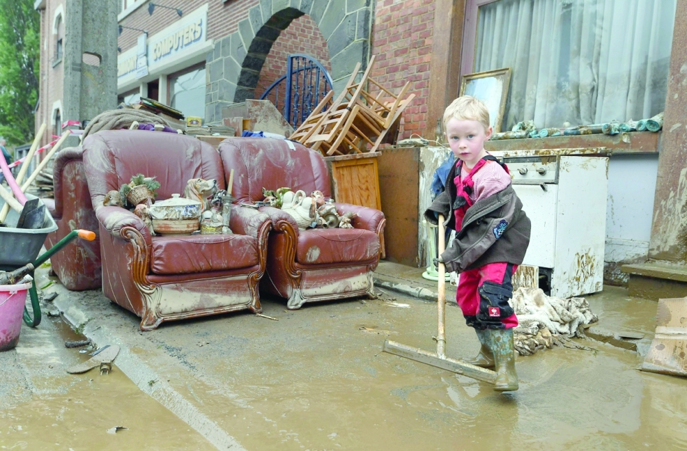 A young resident helps clean-up outside his home following heavy rains and floods in the town of Rochefort, Belgium, on Saturday. - AFP
