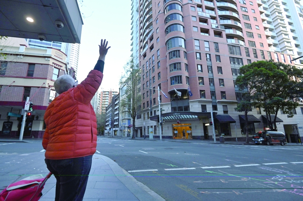 A woman waves to her family members in quarantine at a hotel in Sydney on Saturday, after authorities ordered new restrictions. - AFP 
