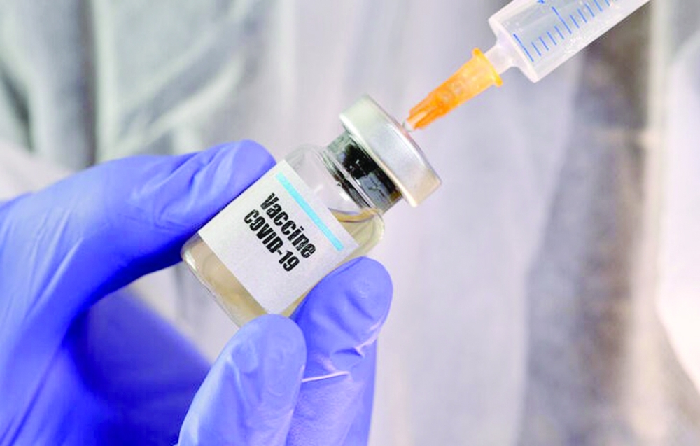 FILE PHOTO: A woman holds a small bottle labeled with a "Vaccine COVID-19" sticker and a medical syringe in this illustration