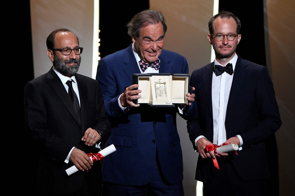 Iranian director Asghar Farhadi (L) and Finnish director Juho Kuosmanen (R) pose with US director Oliver Stone 