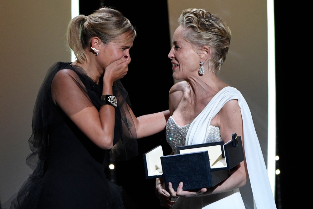French director Julia Ducournau (L) reacts as US actress Sharon Stone hands her the Palme d'Or for her film "Titane" 