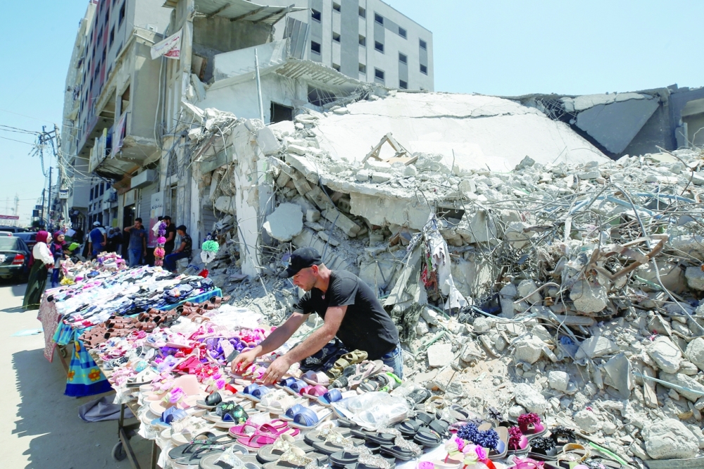 A Palestinian sells shoes on a stall near the rubble of his old shoe store that has been destroyed in an Israeli air strike ahead of Eid al Adha in Gaza City. - Reuters
