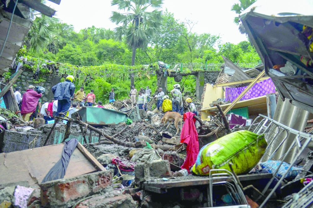 National Disaster Response Force and other rescue team personnel inspect the site of the landslide in a slum area in Mumbai. - AFP 
