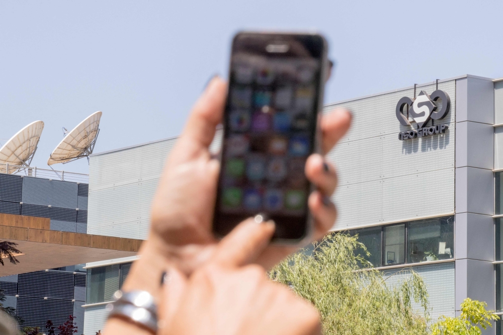 A woman uses her iPhone in front of the building housing the Israeli NSO group 'Pegasus', in Herzliya, near Tel Aviv. - AFP File Photo