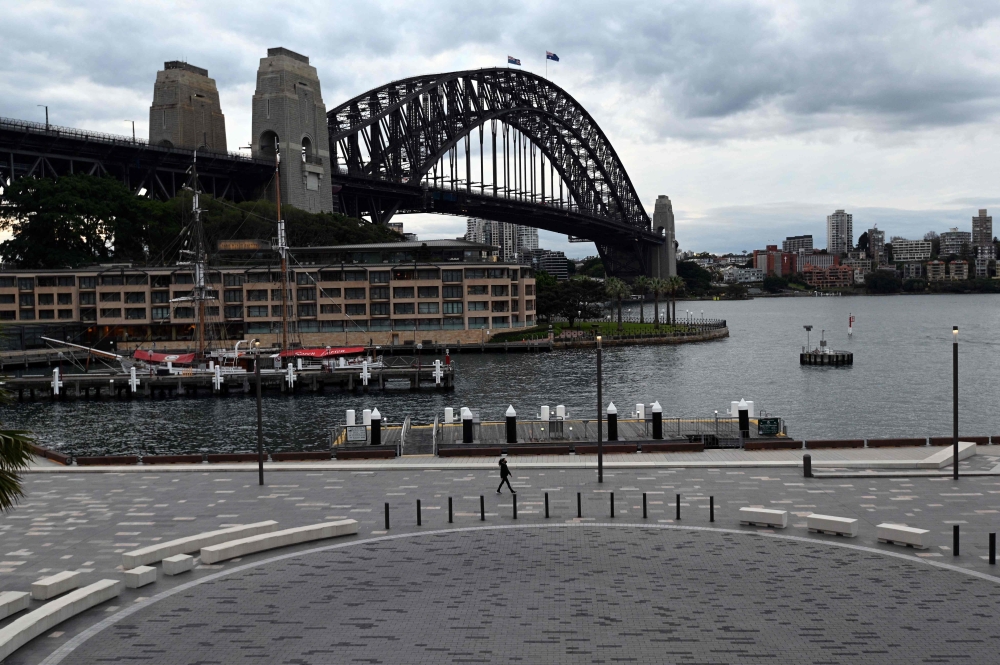 A lone pedestrian walk along the quiet Sydney Harbour amid a lockdown in Melbourne and Sydney as Australia seeks to contain a surge in coronavirus cases. - AFP 