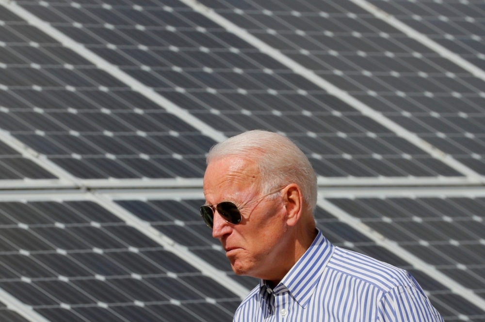 US President Joe Biden walks past solar panels at the Plymouth Area Renewable Energy Initiative in New Hampshire. — Reuters