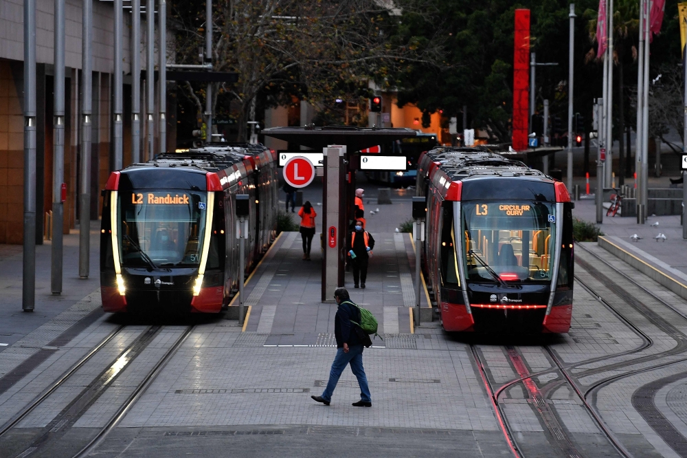 A man wearing a face mask walks towards tram station at Circular Quay in Sydney amid a lockdown in Melbourne and Sydney. - AFP 

