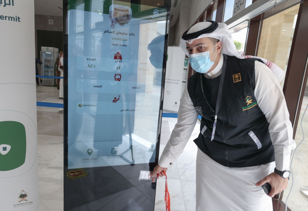 A Saudi member of staff scans a pilgrim's Haj card, allowing contactless access to religious sites, accommodation and transport, at a reception centre in Mecca. - AFP  