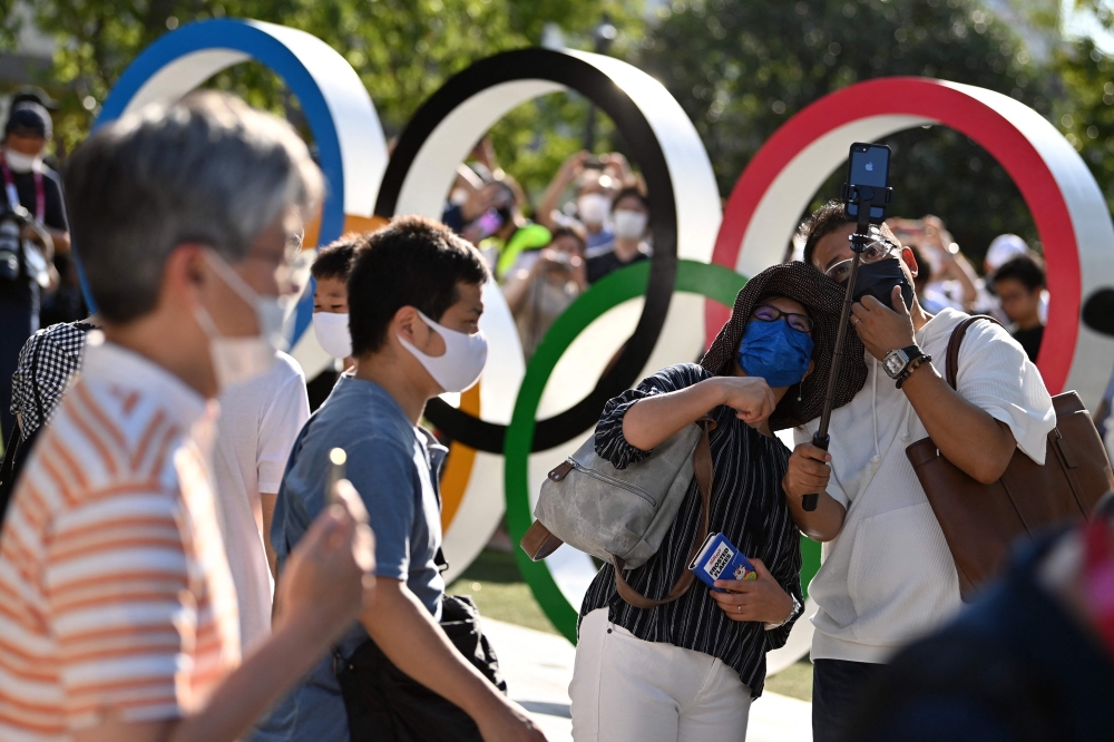 People pose in front of the Olympic rings outside the Olympic stadium in Tokyo, on July 23, 2021, ahead of Tokyo 2020 Olympic games opening ceremony. 

