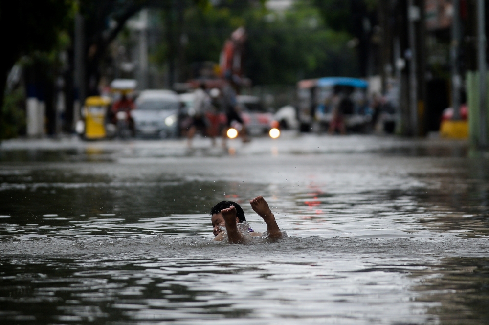 A boy swims on a flooded street following heavy rains, in Manila, Philippines, July 24, 2021. REUTERS/Lisa Marie David
