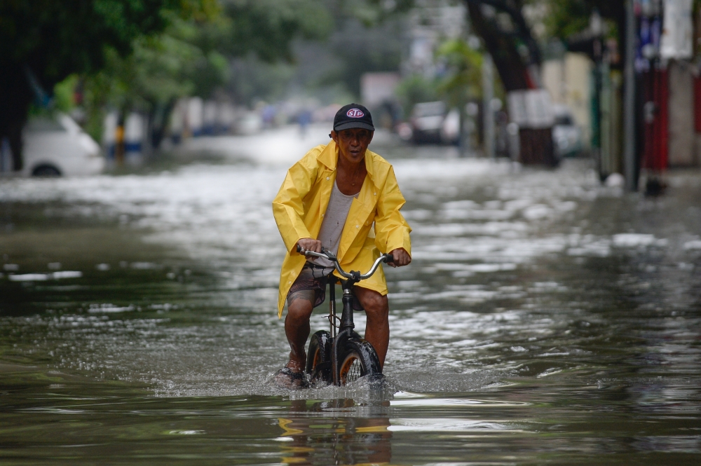 A man on a bicycle wades through a flooded street in Manila, Philippines, July 24, 2021. REUTERS/Lisa Marie David
