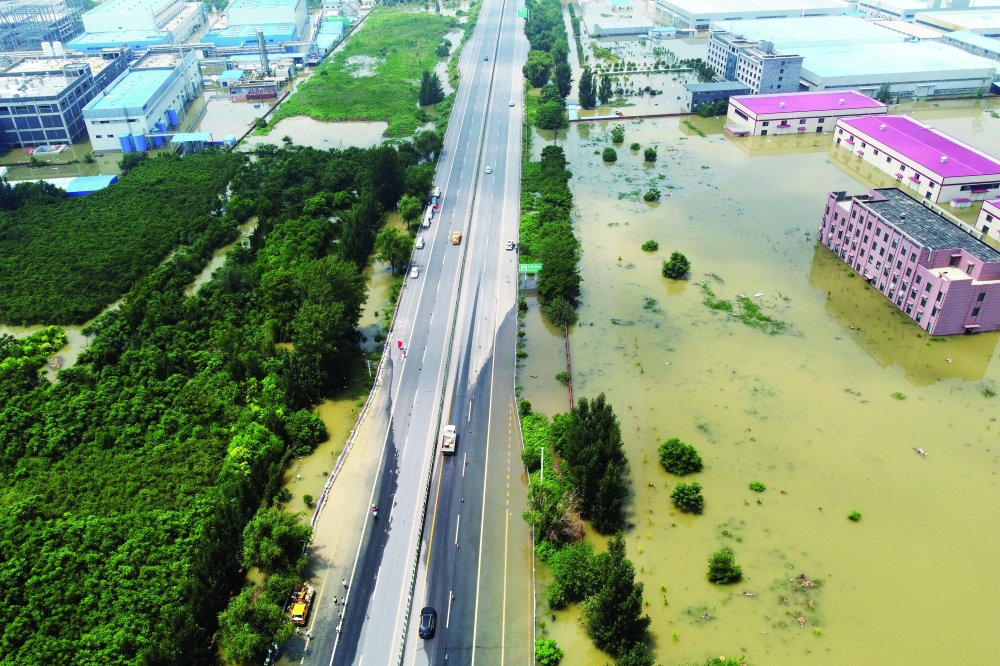 An aerial view shows flooded industrial buildings by a highway following heavy rainfall in Xinxiang, Henan province, on Saturday. - Reuters