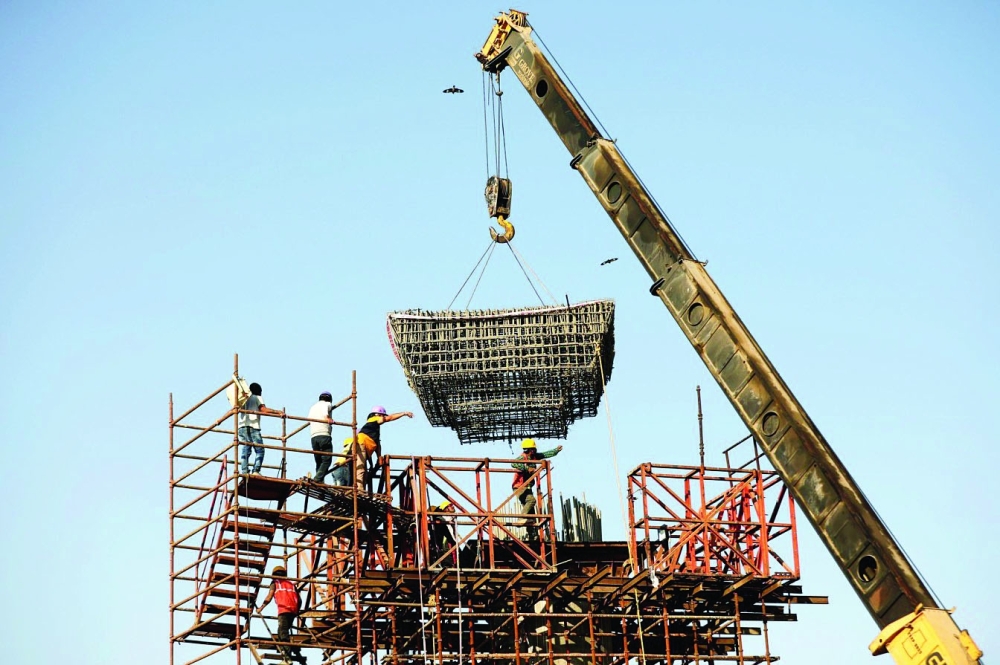 Workers build a pillar at the site of the metro railway flyover under construction in Ahmedabad, India. — Reuters