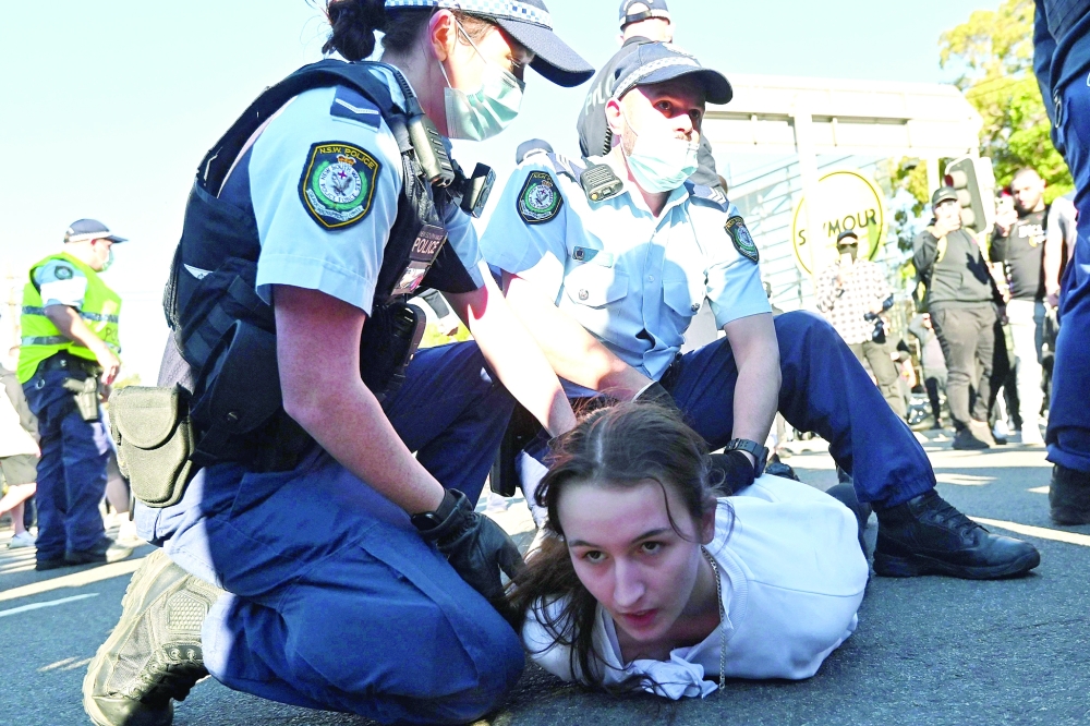 Police officers detain a protestor during a rally in Sydney as thousands of people gathered to demonstrate against the city's month-long stay-at-home orders. - AFP

