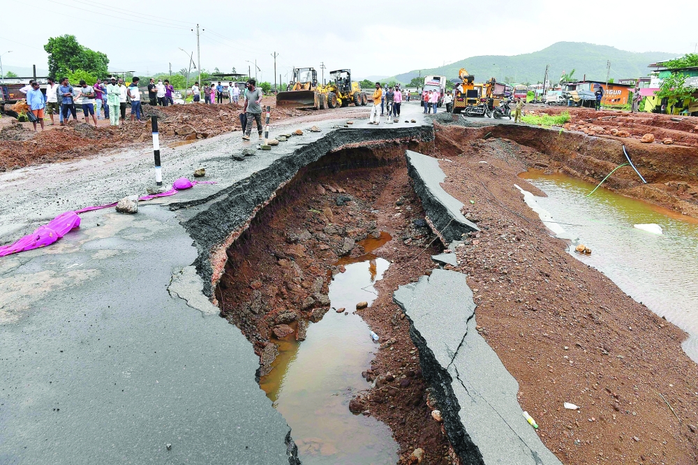 People gather along a section of highway partially washed away from the rain at Mahad with nearly 100,000 others evacuated in Maharashtra.- AFP

