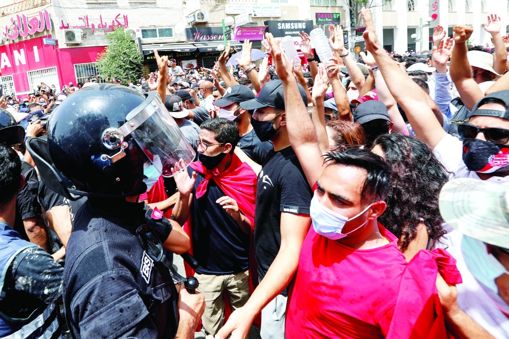 Demonstrators gather in front of police officers standing guard during an anti-government protest in Tunis. - Reuters