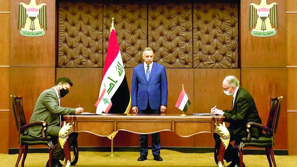 Iraqi Prime Minister Mustafa al Kadhemi (C) looks on as Lebanon's energy minister Raymond Ghajar (L) and Iraq's Finance Minister Ali Allawi sign bilateral agreements in Baghdad. - AFP