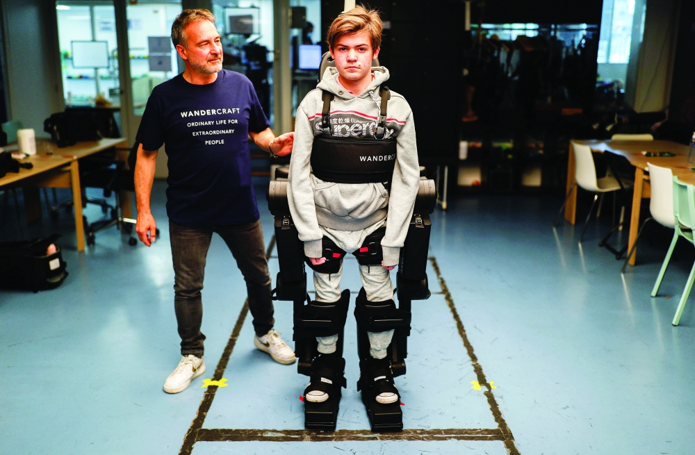 Jean-Louis Constanza helps his son Oscar using a robot exoskeleton at the company headquarters in Paris. - Reuters
