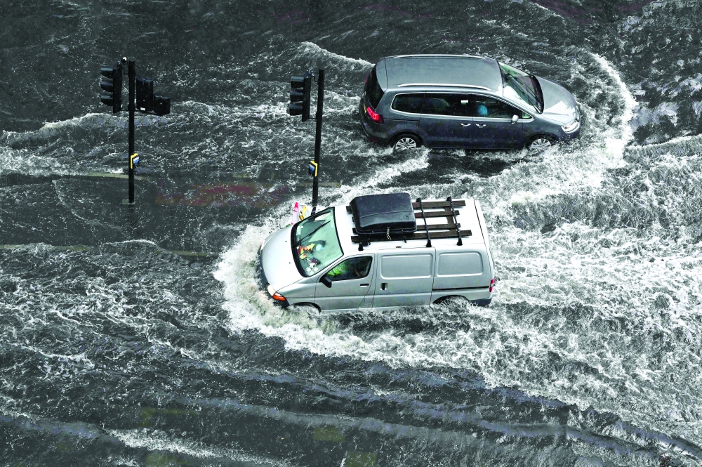 Vehicles drive through deep water on a flooded road in The Nine Elms district of London during heavy rain. - AFP