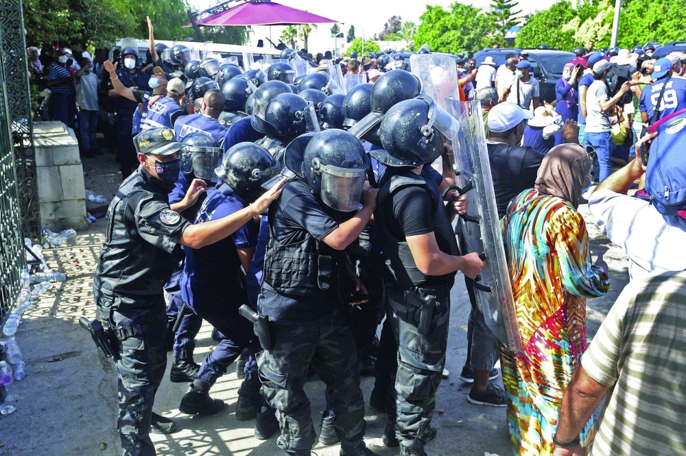 Tunisian security officers hold back protesters outside the parliament building in the capital Tunis following a move by the president to suspend the country's parliament and dismiss the Prime Minister. - AFP
