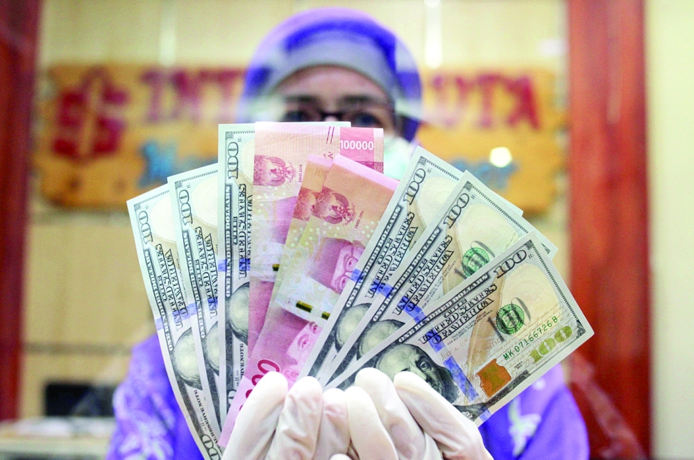 A woman holds Indonesian rupiah and US dollar bills inside a bank in Jakarta. — Reuters
