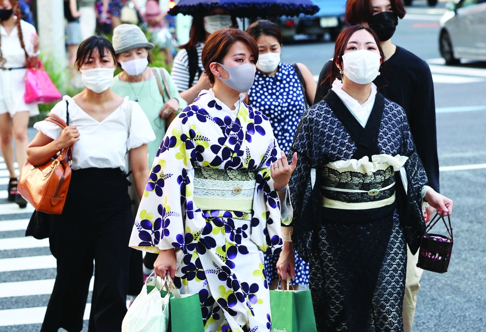 Women in traditional costumes and wearing protective masks amid Covid-19 outbreak make their way in Tokyo, on Tuesday. - Reuters
