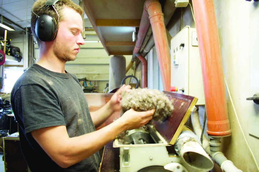 Pall Jonsson, puts eiderdown in a spinning machine that slowly catapults all the brittle dirt out of it at the King Eider company in Stykkisholmur, Iceland, on July 5, 2021. On a remote island in Breidafjordur Bay off the west coast of Iceland, a thousand-year-old harvest takes place, a hunt for elusive eiderdown, which is used to make some of the world's best duvets and quilts. The handpicked down sells for thousands of euros a kilogram, catering to those looking for exclusive products.
 (Photo by Jeremie RICHARD / AFP)

