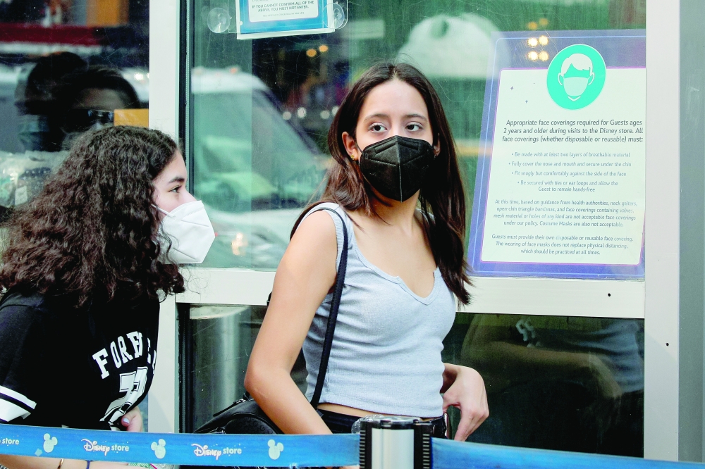 People wear masks against Covid-19, following the CDC recommendation that fully vaccinated Americans wear masks as they enter the Disney Store in Times Square in New York City, on Tuesday. - Reuters