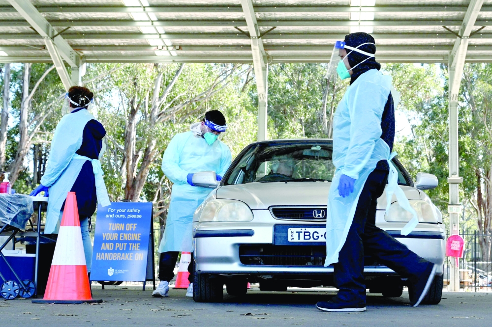 Health workers taking swab samples from residents at a Covid-19 drive-through testing clinic in Sydney. - AFP