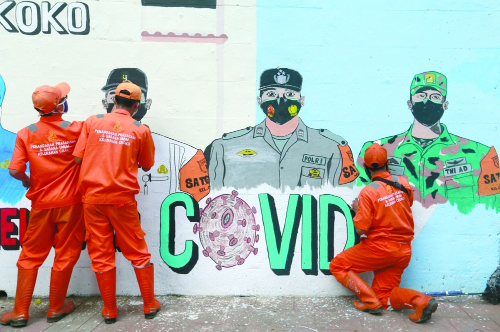 Municipality workers finish the mural promoting awareness of the coronavirus disease as cases surge in Jakarta. - Reuters 
