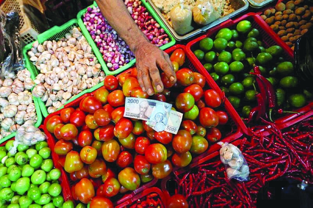 A vendor takes money from the customer at a traditional market in Jakarta. — Reuters