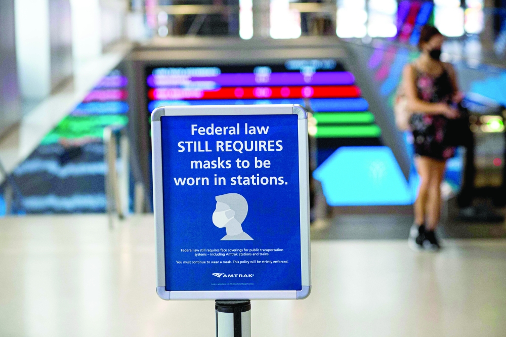 A woman walks past a sign calling for mask wearing at Penn station in New York on Monday. — AFP