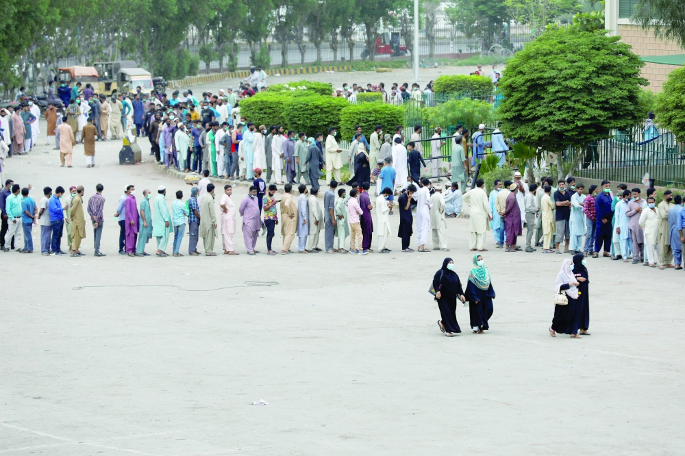Residents line up to receive a vaccine against Covid-19 at a vaccination facility in Karachi, on Tuesday. — Reuters