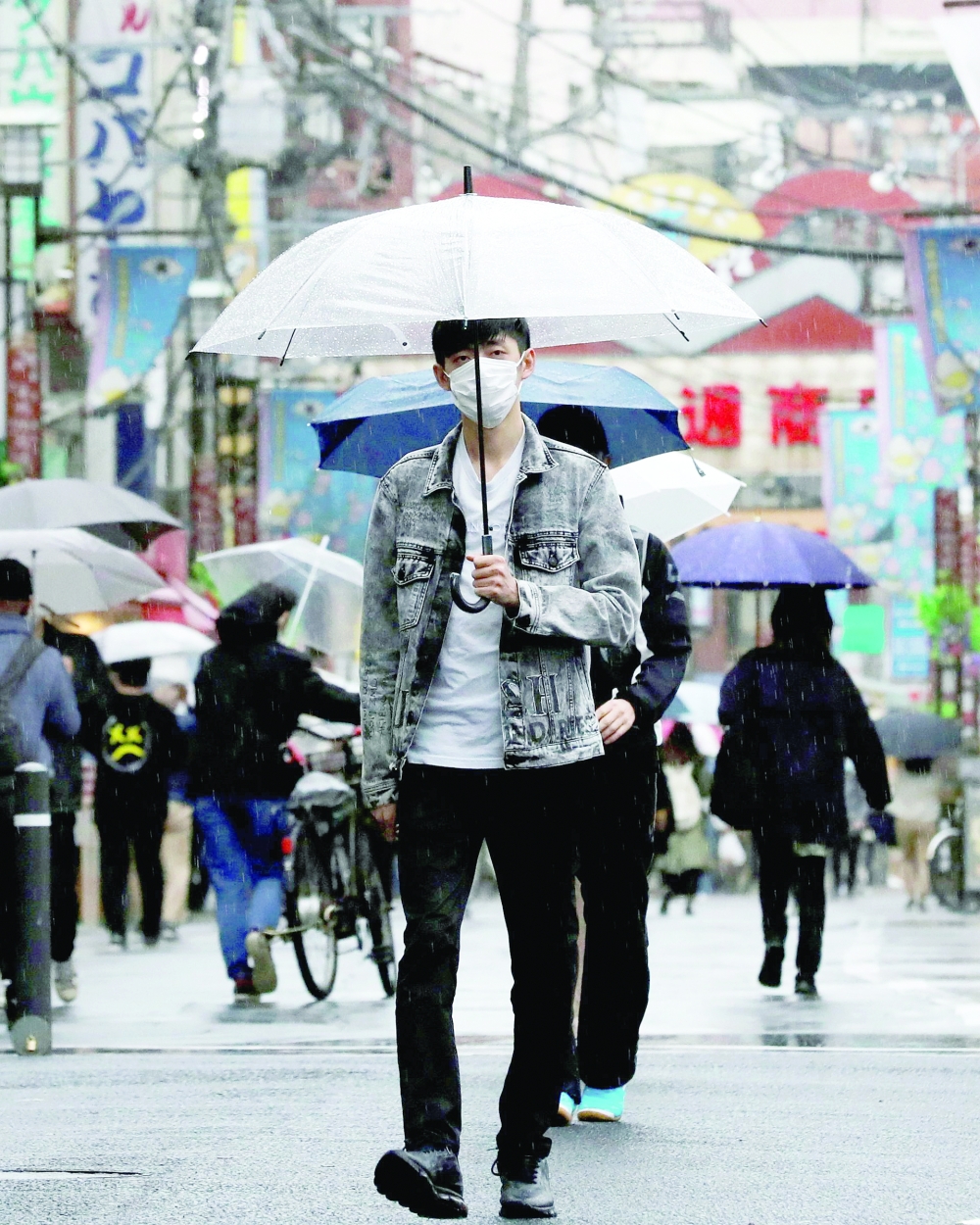 A man wearing a protective face mask, amid the Covid pandemic, makes his way at a local shopping street in Tokyo. - Reuters