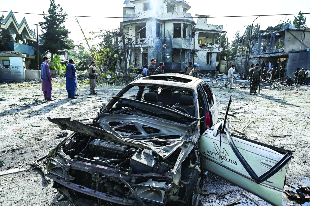 Afghan security personnel inspect the site a day after a car bomb explosion near the wreckage in Kabul on Wednesday. - AFP