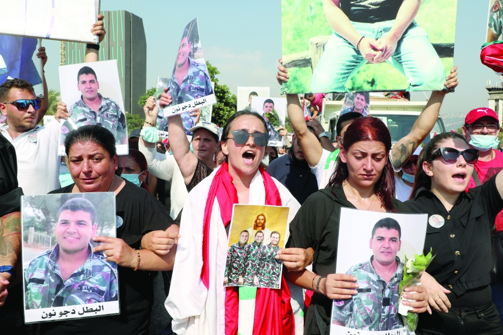 Family members of some of the victims of last year's Beirut port blast march while carrying their pictures, as Lebanon marks the one-year anniversary of the explosion in Beirut, on Wednesday. - Reuters