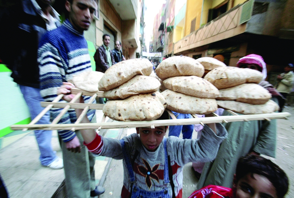 An Egyptian child carries a tray of bread in Cairo. - Reuters