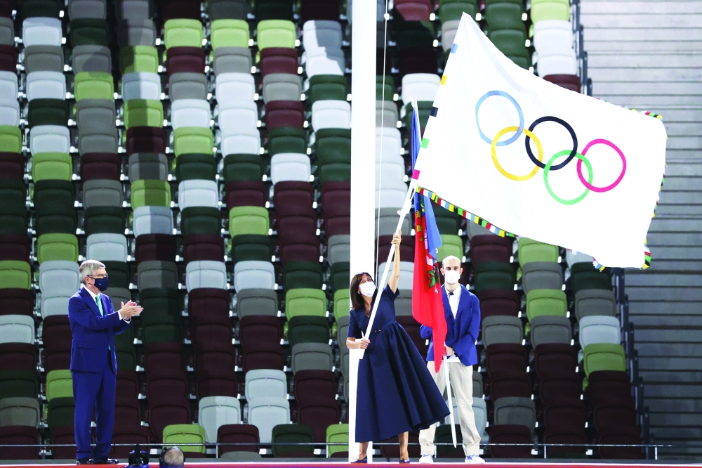 IOC President Thomas Bach applauds as the Mayor of Paris, Anne Hidalgo waves the Olympic flag. -- Reuters