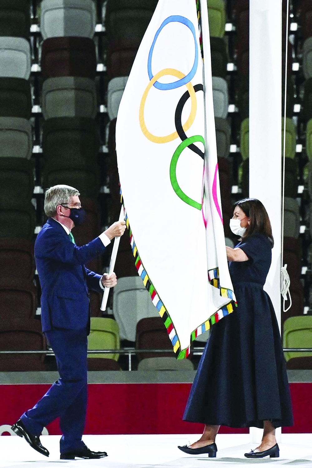 IOC President Thomas Bach hands-over the Olympic flag to Paris' mayor Anne Hidalgo. -- AFP