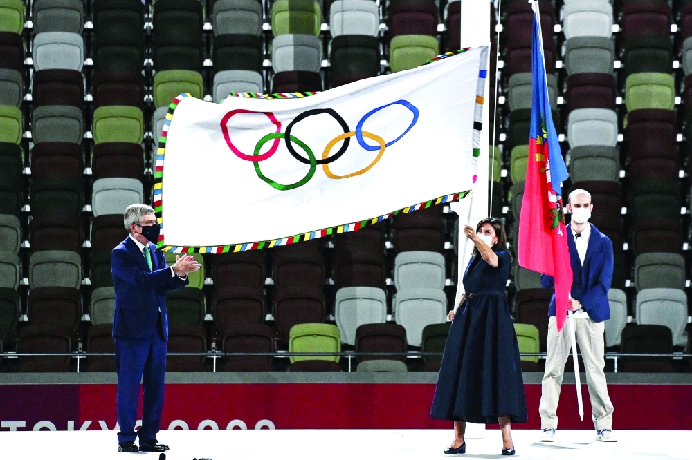 Paris' mayor Anne Hidalgo waves the Olympic flag next to IOC President Thomas Bach. -- AFP  