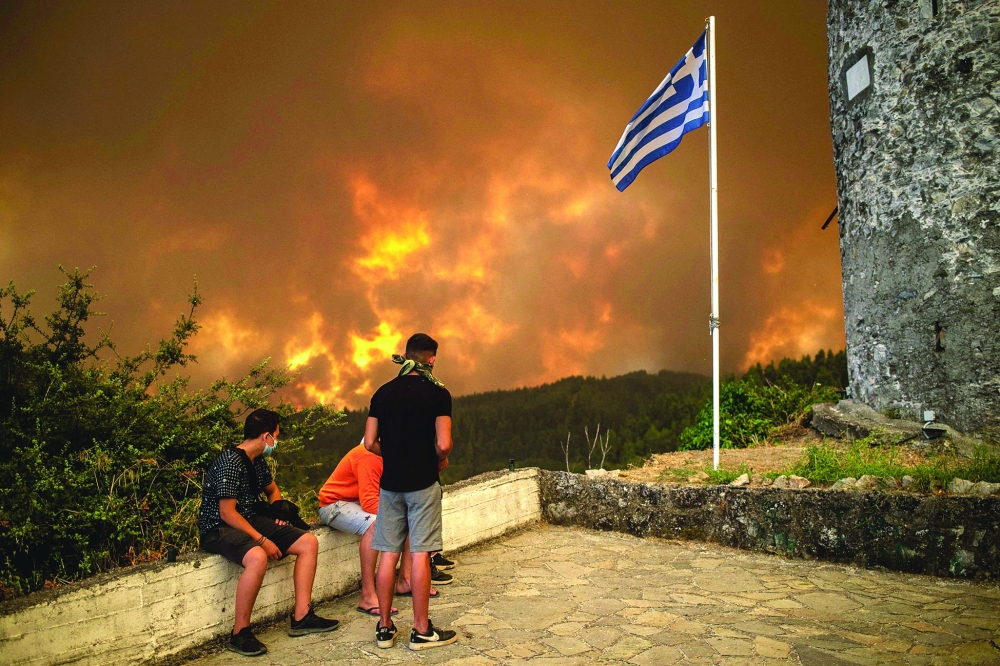 Local residents look at the wildfire approaching the village of Gouves on Evia (Euboea) island, second largest Greek island, on Sunday. -- AFP