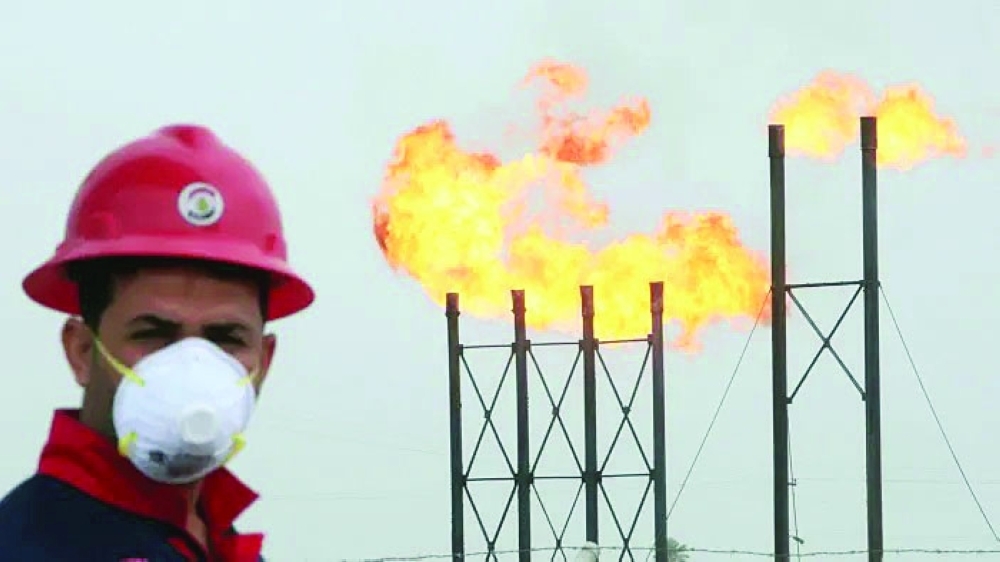 Oil flares are seen behind a man at Nahr Bin Umar oilfield in Iraq. — Reuters