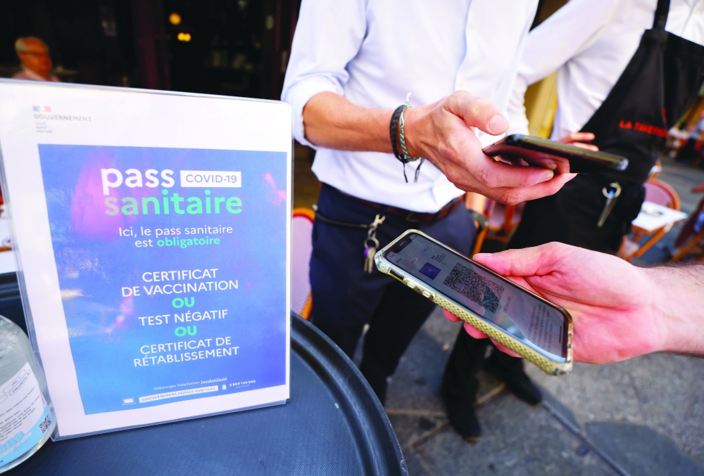 A man shows his coronavirus disease (COVID-19) health pass at a restaurant as France brings on tougher restrictions where a proof of immunity will now be required to access most public spaces and to travel by inter-city train in Nice on Monday. -- Reuters