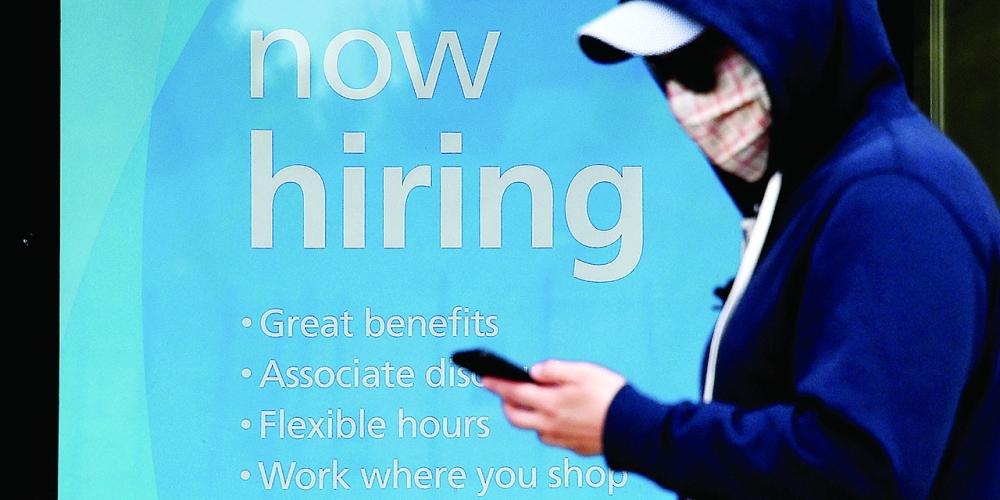 A man in a mask walks past job advertisement in New York. — AFP