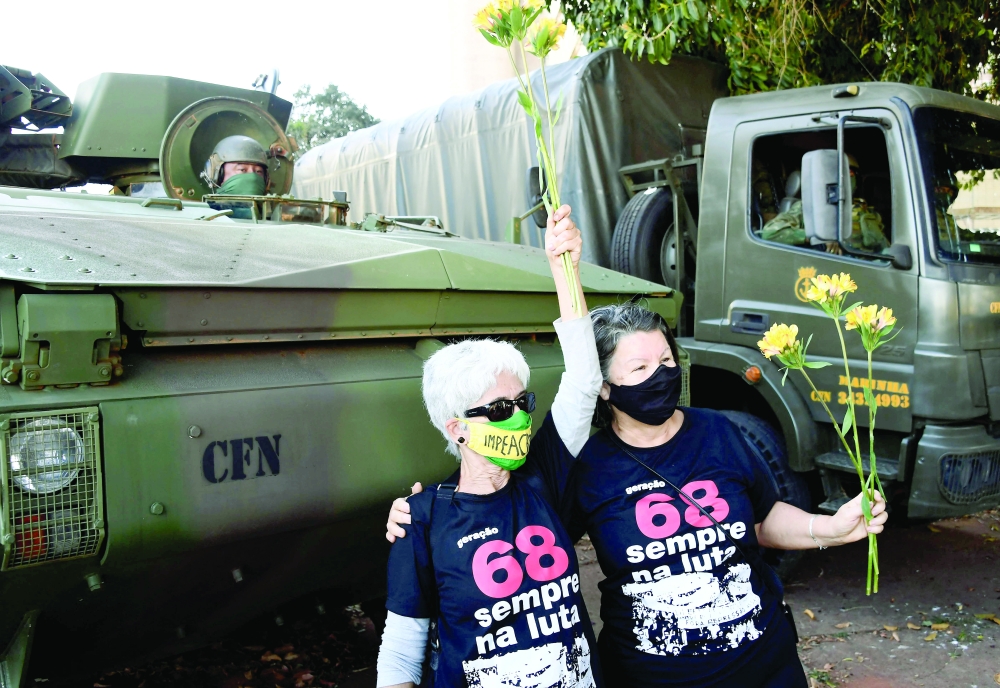 Demonstrators against a military vehicles parade in front of the Planalto Palace in Brasilia, hold flowers next to an armoured carrier, on Tuesday. -- AFP
